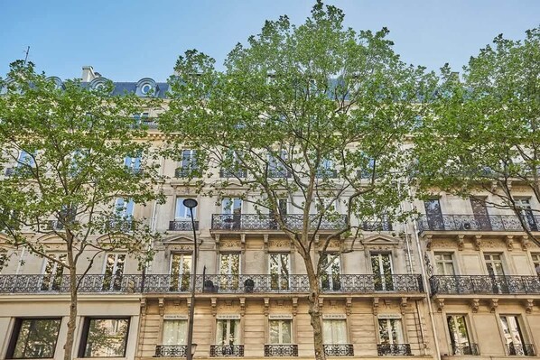 A multi-story building with classical architecture, featuring balconies with wrought iron railings and large windows.