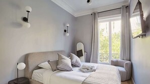 A bedroom with a bed, bedside table, and a window with curtains. - New and Exceptional apartment Madeleine/Concorde (Paris)
