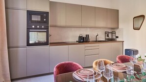 A modern kitchen with stainless steel appliances, a dining area with a table set for four, and a minimalist design. - New and Exceptional apartment Madeleine/Concorde (Paris)