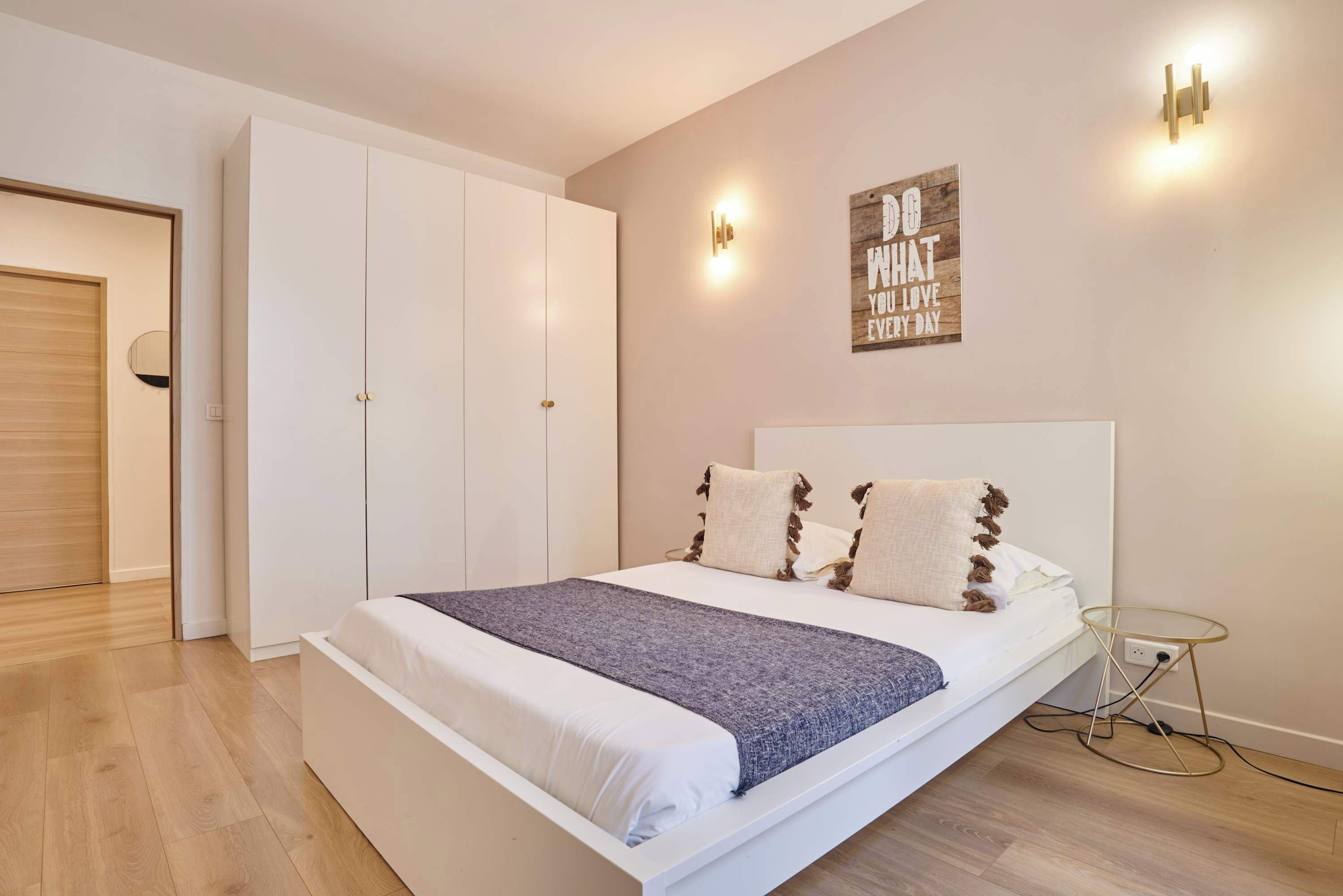 A bedroom with a bed, wardrobe, bedside table, and wall decor.