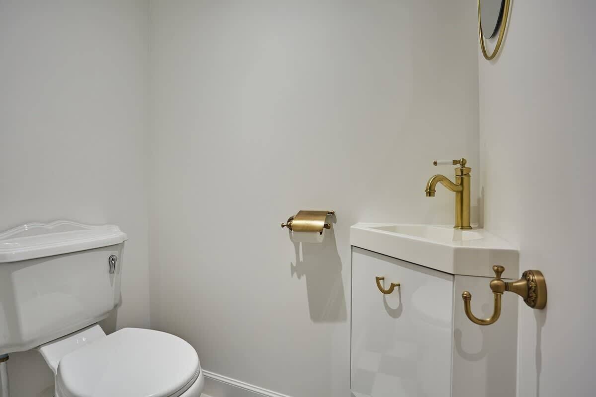 A bathroom with a white toilet, a gold faucet, and a gold toilet paper holder.