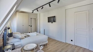 Un dormitorio moderno con una cama, una mesita de noche y un televisor montado en la pared.