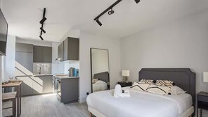 Ein modernes Hotelzimmer mit einem großen Bett, einem Schreibtisch und einer Küchenzeile.