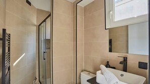 Ein modernes Badezimmer mit Duschkabine, Toilette und Waschbecken mit Handtuch.