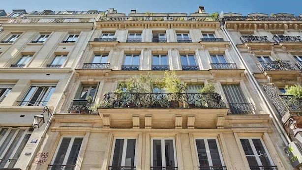 A multi-story building with a classic architectural style, featuring balconies with wrought iron railings and a central garden area. - Sublim apartment Beaubourg/Le Marais (Paris)