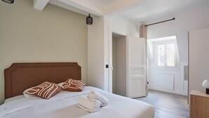 A bedroom with a bed, pillows, a bedside table, and a door leading to another room. - Sublim apartment Beaubourg/Le Marais (Paris)