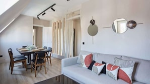 A modern living room with a dining area, featuring a sofa with patterned cushions, a dining table set for four, and a ceiling with track lighting. - Sublim apartment Beaubourg/Le Marais (Paris)