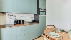 Eine kleine Küche mit Türkis-Schränken, einer Marmor-Spritzschutzleiste und einem Holzespeisetisch, gedeckt mit Geschirr und Besteck.