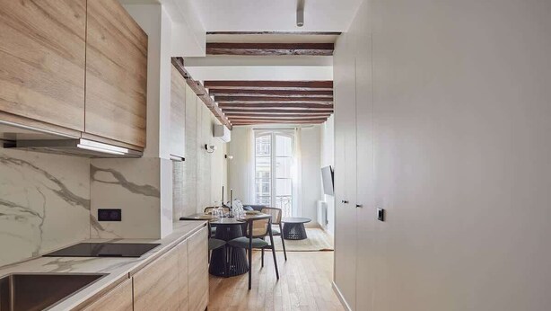 A modern kitchen with wooden cabinets, a marble backsplash, and a dining area with a round table and chairs. - New Apartment Center of Paris Place de la Bourse (Paris)