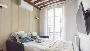 A bedroom with a bed, a window, and a wall-mounted TV. - New Apartment Center of Paris Place de la Bourse (Paris)