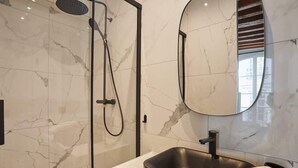 A modern bathroom with a glass-enclosed shower, a black sink, and a large mirror. - New Apartment Center of Paris Place de la Bourse (Paris)