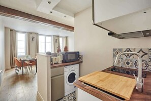 Uma cozinha compacta com máquina de lavar, micro-ondas e bancada de madeira.