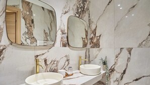 A bathroom with two sinks, marble walls, and two mirrors. - Elegant Apartment St Germain des prés Luxembourg Park (Paris)
