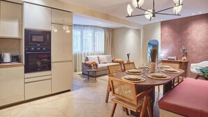 A modern kitchen with built-in appliances, a dining area with a wooden table and chairs, and a cozy seating area with a sofa and a small side table. - Elegant Apartment St Germain des prés Luxembourg Park (Paris)