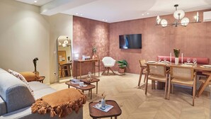 A modern living room with a sofa, coffee table, dining table with chairs, a TV, and a chandelier. - Elegant Apartment St Germain des prés Luxembourg Park (Paris)