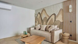 A modern living room with a beige sofa, a wooden coffee table, and a textured wall. - Spacious AC flat Luxembourg St Germain des près (Paris)