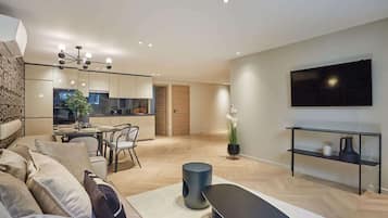 Un salon moderne avec un canapé, une table basse et un téléviseur fixé au mur.