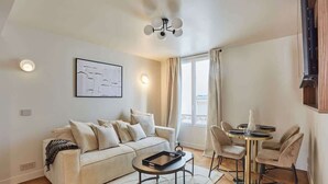 A modern living room with a sofa, a coffee table, and a dining area with chairs and a table.