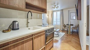 A modern kitchen with wooden cabinets, a stainless steel sink, and a built-in oven. - New apartment Center of Paris/Le Marais (Paris)