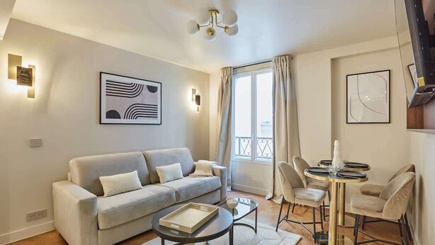 A modern living room with a sofa, coffee table, and dining area with chairs and a table. - New apartment Center of Paris/Le Marais (Paris)