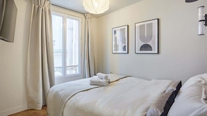 A hotel room with a bed, a window with curtains, and two framed artworks on the wall. - New apartment Center of Paris/Le Marais (Paris)