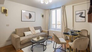 A modern living room with a sofa, coffee table, and dining area. - New apartment Center of Paris (Paris)