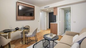 A modern living room with a dining area, a TV mounted on the wall, and a kitchen visible through an open door. - New apartment Center of Paris (Paris)