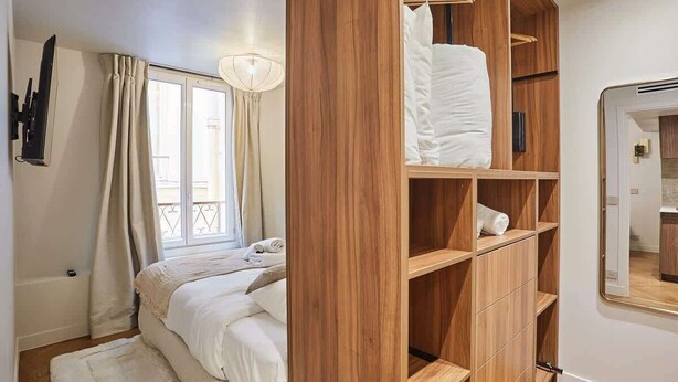A bedroom with a bed, wooden wardrobe, and a mirror. - New apartment Center of Paris (Paris)