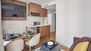 Una cocina moderna con armarios de madera, horno empotrado y comedor con mesas y sillas redondas.