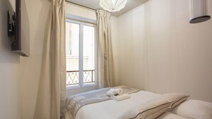 A bedroom with a bed, curtains, a window, and a ceiling light.