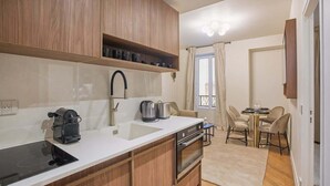 A modern kitchen with wooden cabinets, a built-in stove, and a sink. There is a dining area with a table and chairs.