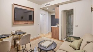 A modern living room with a flat-screen TV, a dining area with a round table, and a sofa.