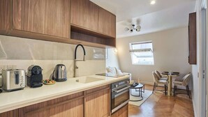 Une cuisine moderne avec des meubles en bois, un four encastré et un évier. On y trouve également un coin repas avec une table et des chaises.