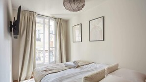 A bedroom with a bed, a window with curtains, and two framed pictures on the wall. - New apartment Center of Paris/Le Marais (Paris)