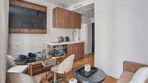 A modern kitchen with wooden cabinets, a built-in oven, and a dining area with a round table and chairs.