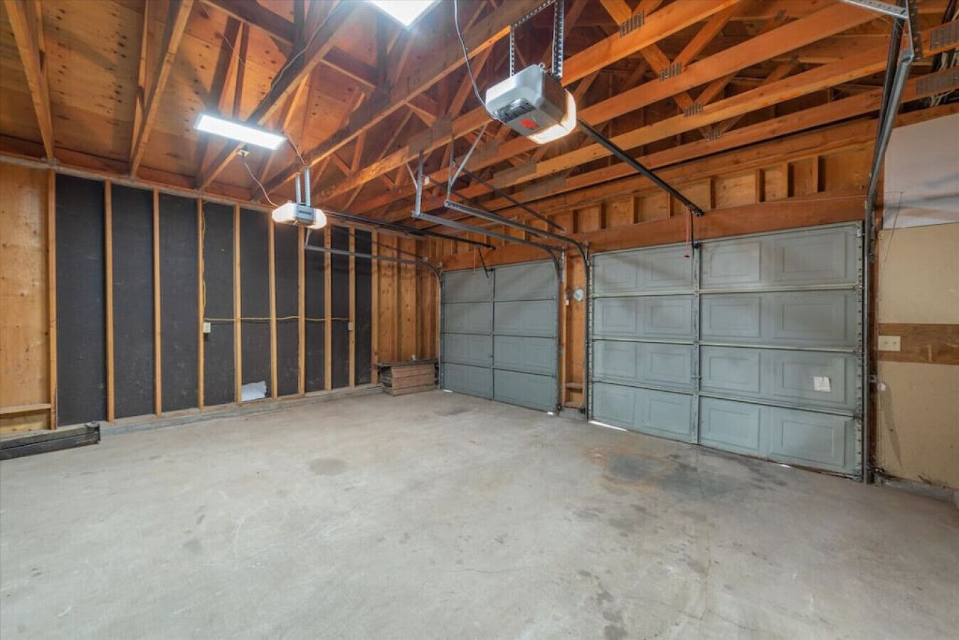 A large, open garage with a concrete floor and wooden beams on the ceiling.