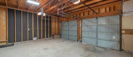 A large, open garage with a concrete floor and wooden beams on the ceiling.