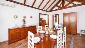 Un comedor con una mesa de madera, sillas blancas y un aparador de madera con cajones.