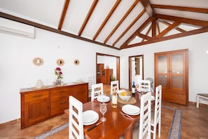 A dining area with a wooden table, white chairs, and a wooden cabinet with drawers.
