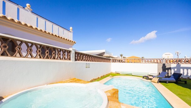 Zona de piscina con dos jacuzzis y sillas de descanso.