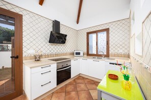 Una cocina moderna con armarios blancos, horno empotrado, microondas y ventana sobre el fregadero.