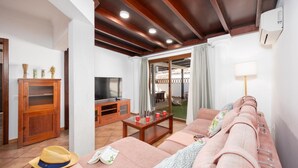 Una sala moderna con techo de madera, televisor, sofá, mesa de centro y comedor.