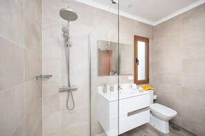Un baño moderno con cabina de ducha de vidrio, tocador blanco y retrete.