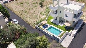 Ein modernes, zweistöckiges Haus mit Pool, überdachter Terrasse und Garage.