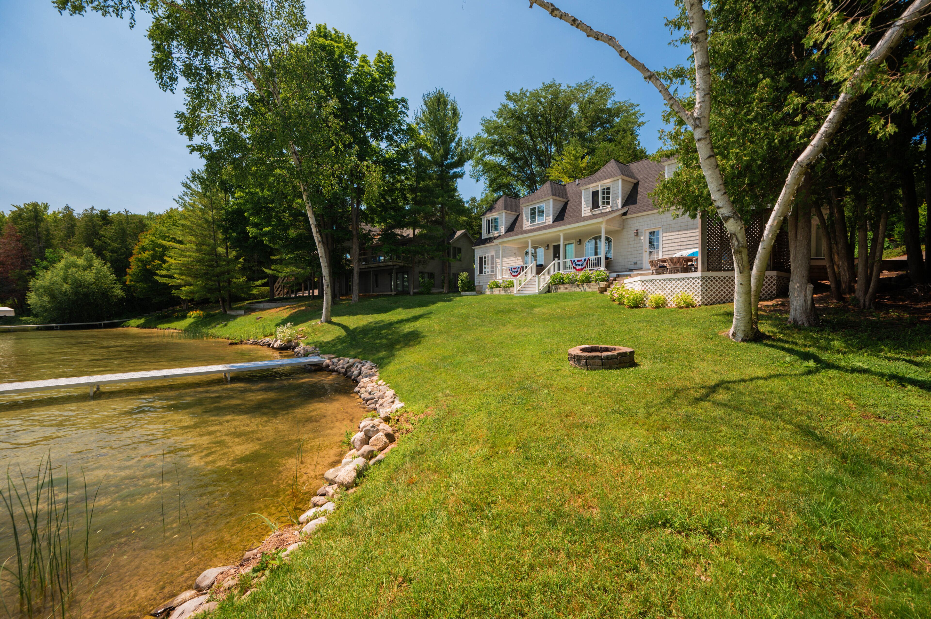 A large house with a well-maintained lawn, a pond, and a wooden deck.
