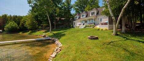 A large house with a well-maintained lawn, a pond, and a wooden deck.