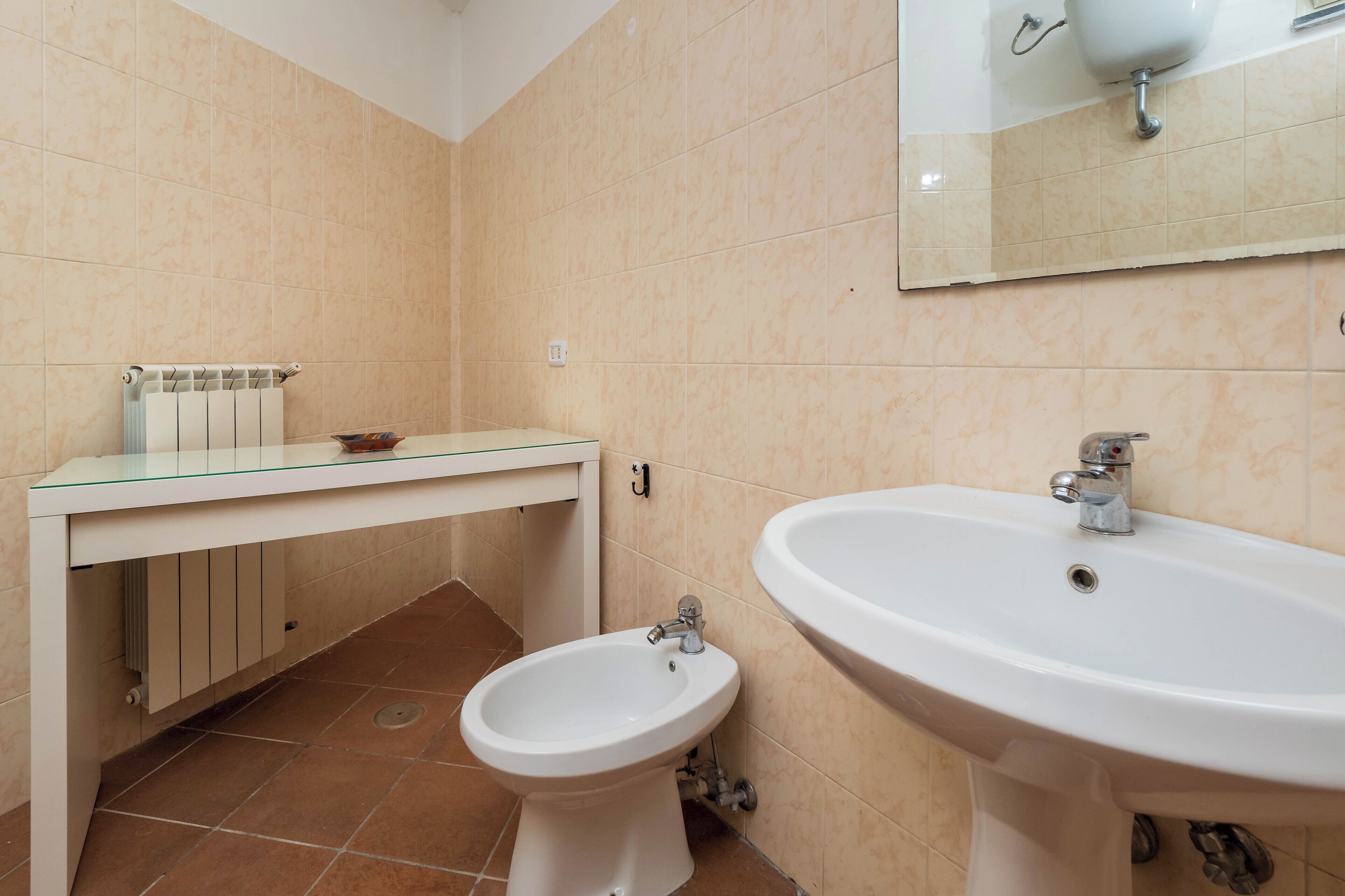 Ein Badezimmer mit einer Waschtischplatte aus Glas, einem Stand-Bidet und einem wandmontierten Waschbecken.