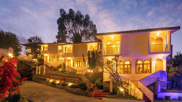 A multi-story building with a grand staircase, multiple balconies, and a well-lit facade. - Mango Hill Kodai (Kodaikanal)