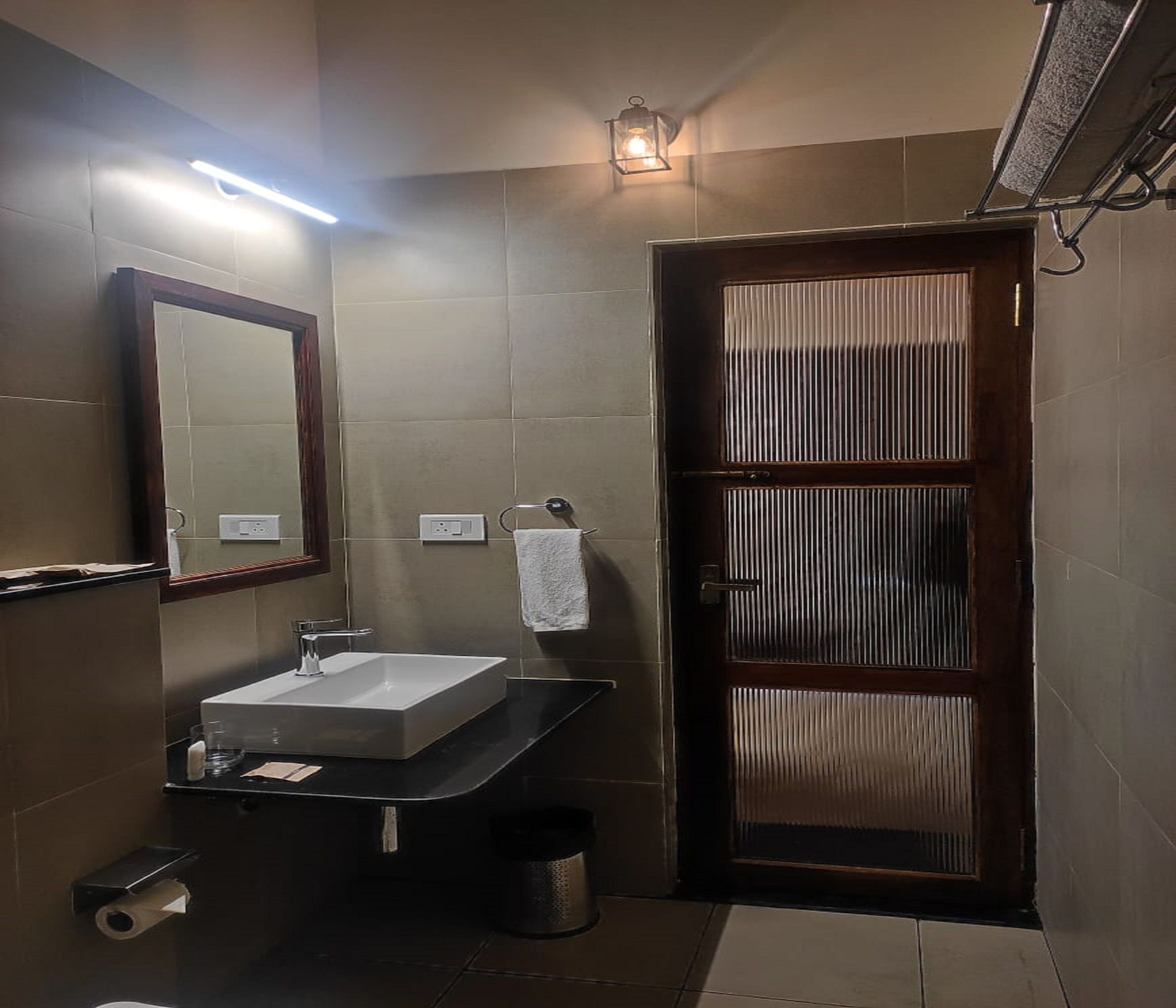 A bathroom with a sink, mirror, towel rack, and a door with vertical blinds.