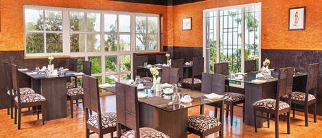 A conference room with a high ceiling, large windows, and a polished orange floor.